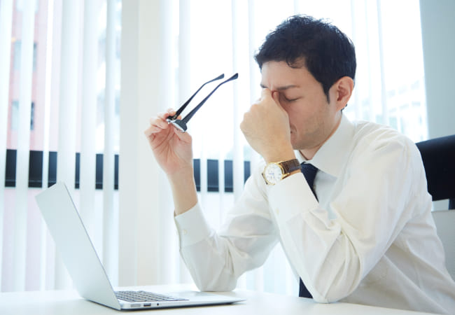 目頭を抑える男性