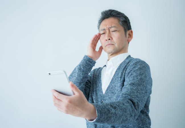 スマホの画面を見にくそうにしている男性